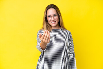 Young caucasian woman isolated on yellow background inviting to come with hand. Happy that you came