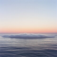 Fototapeta premium A cloud-like mist rising above a calm ocean at dawn