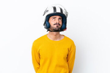 Young caucasian man with a motorcycle helmet isolated on white background and looking up