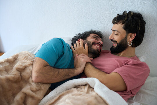 Happy gay couple sharing intimate moments in bed