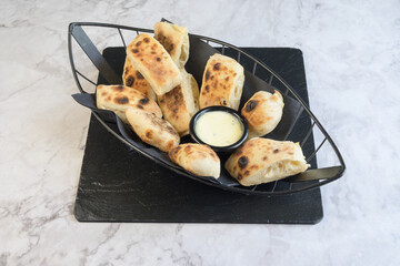 A basket of bread with a dipping sauce
