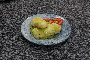 A plate of food with fish and tomato on it