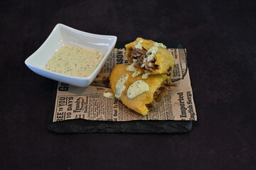 A plate of food with a dip and a newspaper on top