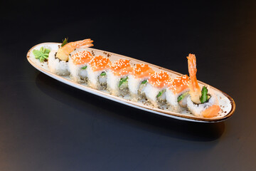 A long roll of sushi with shrimp and seaweed on top