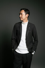 Fototapeta premium A stylish man in a black blazer and white turtleneck looking to the side