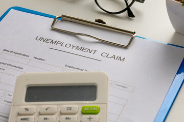 A filled-out unemployment claim form clipped to a board, placed on an office desk, symbolizing economic hardship.