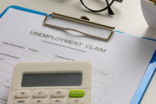 A filled-out unemployment claim form clipped to a board, placed on an office desk, symbolizing economic hardship.