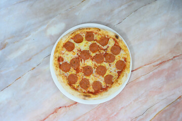 A pizza with pepperoni on it is sitting on a white plate