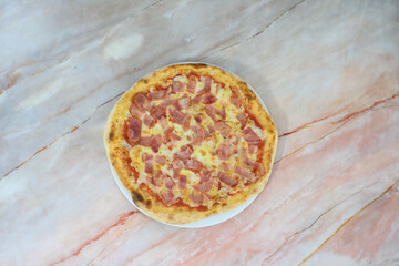 A pizza with ham and cheese on a white plate
