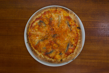 A pizza with a lot of cheese and tomato sauce sits on a wooden table