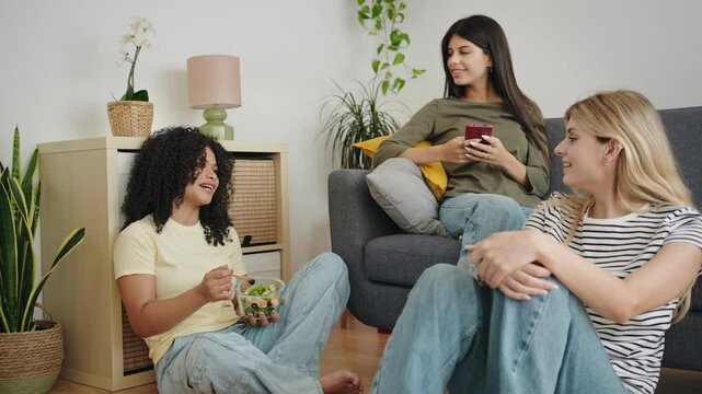 Group of happy flatmate girl friends talking at home while eating 