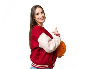 Young beautiful woman playing basketball over isolated chroma key background pointing back