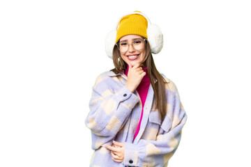 Young woman wearing winter muffs over isolated chroma key background with glasses and smiling