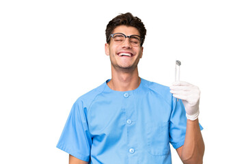 Young dentist man holding tools over isolated background laughing