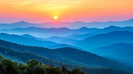 Obraz premium Layered blue mountain range under a bright colorful sunrise sky Trees fill the foreground in the fading light.