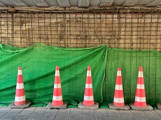 Construction is underway for the reconstruction of the tunnel under the road, on which work is being carried out. Orange traffic cones and tarp over construction wall