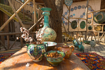 Uzbek traditional dishes, a branch of flowering almonds and a dish with dried apricots in the yard © Shchipkova Elena