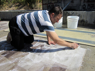 A man in the village washes the carpet with a brush