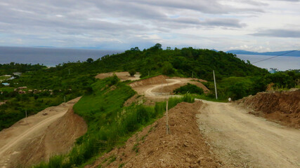 Dirt road in tropical mountains. Dirt winding road on a hillside. The road runs along the mountain range of a tropical island.