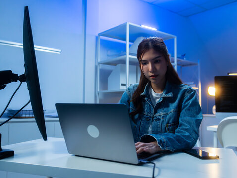 Professional Asian female software Engineer looking at monitor screen, analyzing source code algorithm working on laptop computer in office. Asian female programmer writing code for startup project.