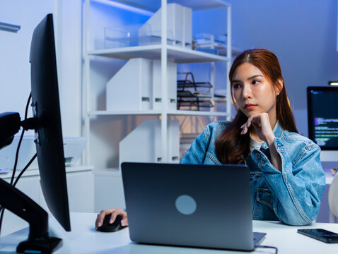 Professional Asian female software Engineer looking at monitor screen, analyzing source code algorithm working on laptop computer in office. Asian female programmer writing code for startup project.