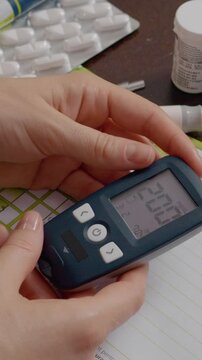 Vertical Screen: A woman examines the high blood sugar result displayed on her glucometer. Concerned, she notes her elevated glucose level while managing diabetes at home.