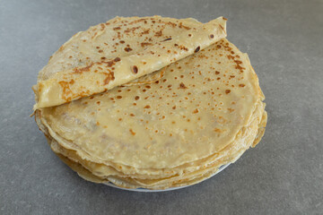 One homemade crepe is rolled up and placed on a plate.