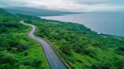 Obraz premium a breathtaking road between lush green hills and the deep blue sea, a peaceful drive through untouched nature, capturing the beauty of the landscape