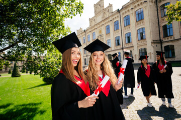 Portrait of group students smile hold diploma mortarboard gown graduation university building...