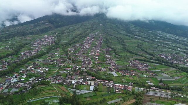 4k aerial footage from the foot of the mountain with rice fields and several beautiful and cool villages. Aerial panorama of the village area and green rice fields at the foot of Mount Merapi