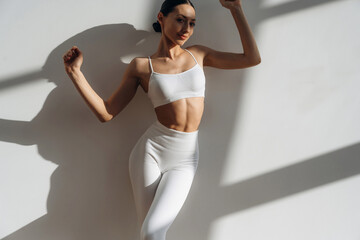 Illuminated by sunlight. Beautiful young woman with slim body type is indoors