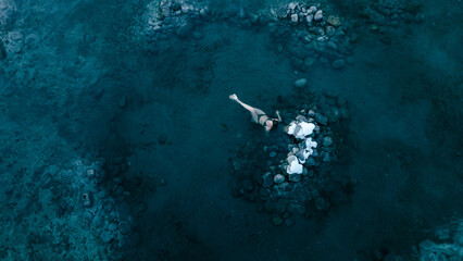 Aerial view of a lone woman relaxing in a stunning thermal spring surrounded by snowy landscapes in...