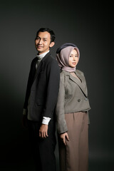 Fashionable couple standing back-to-back in a studio, exuding confidence