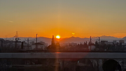 Sunset over urban skyline with mountains, tranquil evening concept, serene nature, peacefulness backdrop