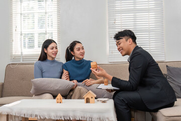 Real estate agent showcasing miniature houses to prospective buyers in a stylish setting.