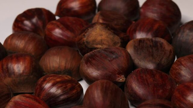 Edible chestnuts (Castanea sativa) rotating in a circle. European sweet chestnuts (marrons), turning. Concept of seasonal food, autumn harvest, and traditional flavors. marrons, chestnuts, rotating, e