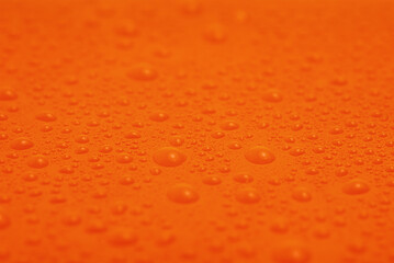Water drops on orange plastic macro photo as a background.