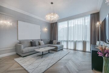 Elegant interior of the living room in the apartment. A room with a panoramic window, parquet floor and a luxurious chandelier. Stylish furniture.
