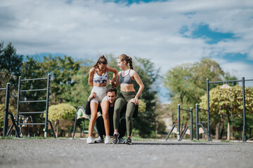 Three people engage in physical exercise in a park setting on a sunny day, enjoying teamwork. Their energetic training reflects a healthy and active lifestyle in nature's beauty.