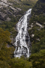 Obraz premium Steall Waterfall, a breathtaking natural wonder in the Scottish Highlands, from rugged cliffs into a lush valley. Trekking adventure leads to panoramic views, where embrace the wild untouched nature.