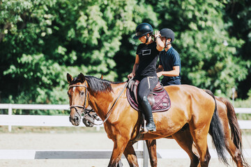 A sunny day showcases two people engaged in horseback riding. Surrounded by lush greenery, they...