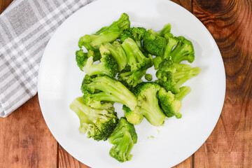 Boiled broccoli on dish on a rustic table, top view