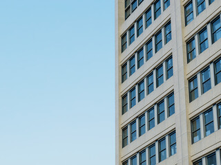 Top corner of a modern office building with clean lines and blue sky.