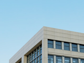 Glass facade of a modern building with geometric design and clear sky.