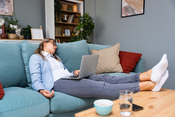 Overworked tired businesswoman sleeping on sofa in home office. Young exhausted girl working from...
