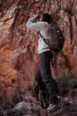 Obraz premium Explorer Using Binoculars to Observe Nature in Mountain Landscape – Tafraoute, MoroccoFebruary 27, 2025