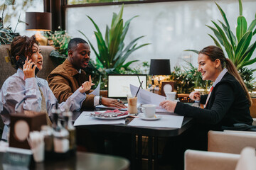 Multicultural people collaborating over a business meeting in a cafe. Presenting ideas and...