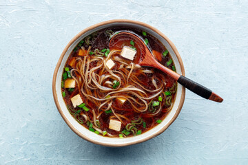 Tofu soup, Japanese cuisine. Miso soup with bean curd and green onions, with soba, buckwheat noodles, overhead flat lay shot