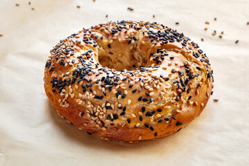 Bagel with sesame seeds, on baking paper, freshly baked