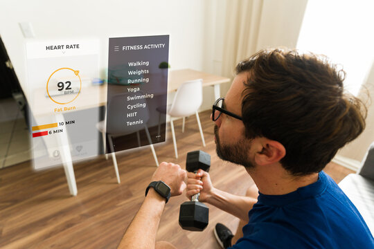 POV of a man exercising with dumbbells at home using augmented reality glasses displaying fitness data and activity options